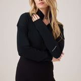 Woman wearing a black outfit with a brand logo on a plain background