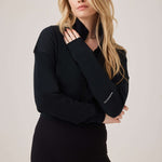 Woman wearing a black outfit with a brand logo on a plain background
